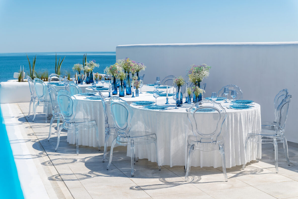 Round tables with white tablecloths and transparent chairs by a pool
